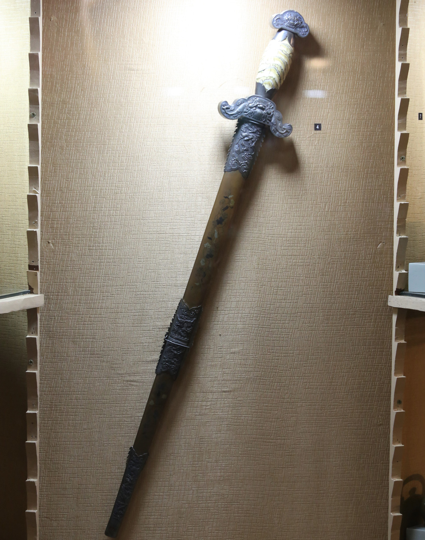 Thanh gươm làm bằng đồng, khảm tam khí thuộc thế kỷ XX. Trong thời đại phong kiến, chỉ vua chúa, quan lại và những người có thế lực mới có thể sở hữu món kim khí này.