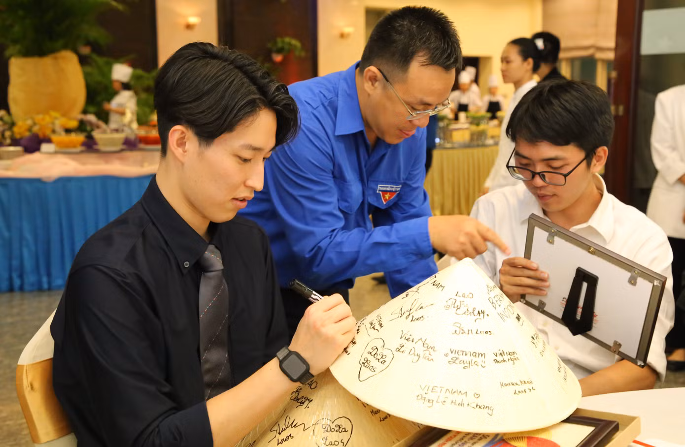 Các đại biểu viết dòng lưu niệm lên nón lá. Các đại biểu viết dòng lưu niệm lên nón lá.