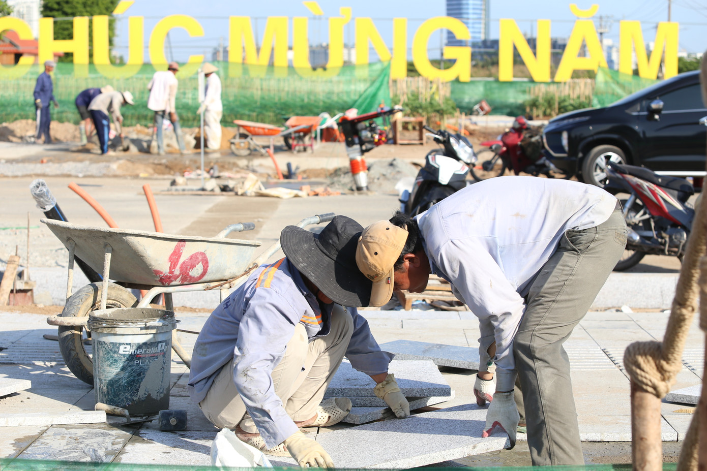 Nhóm công nhân đang thực hiện lát nền trong khuôn viên công viên sát vườn hoa hướng dương.