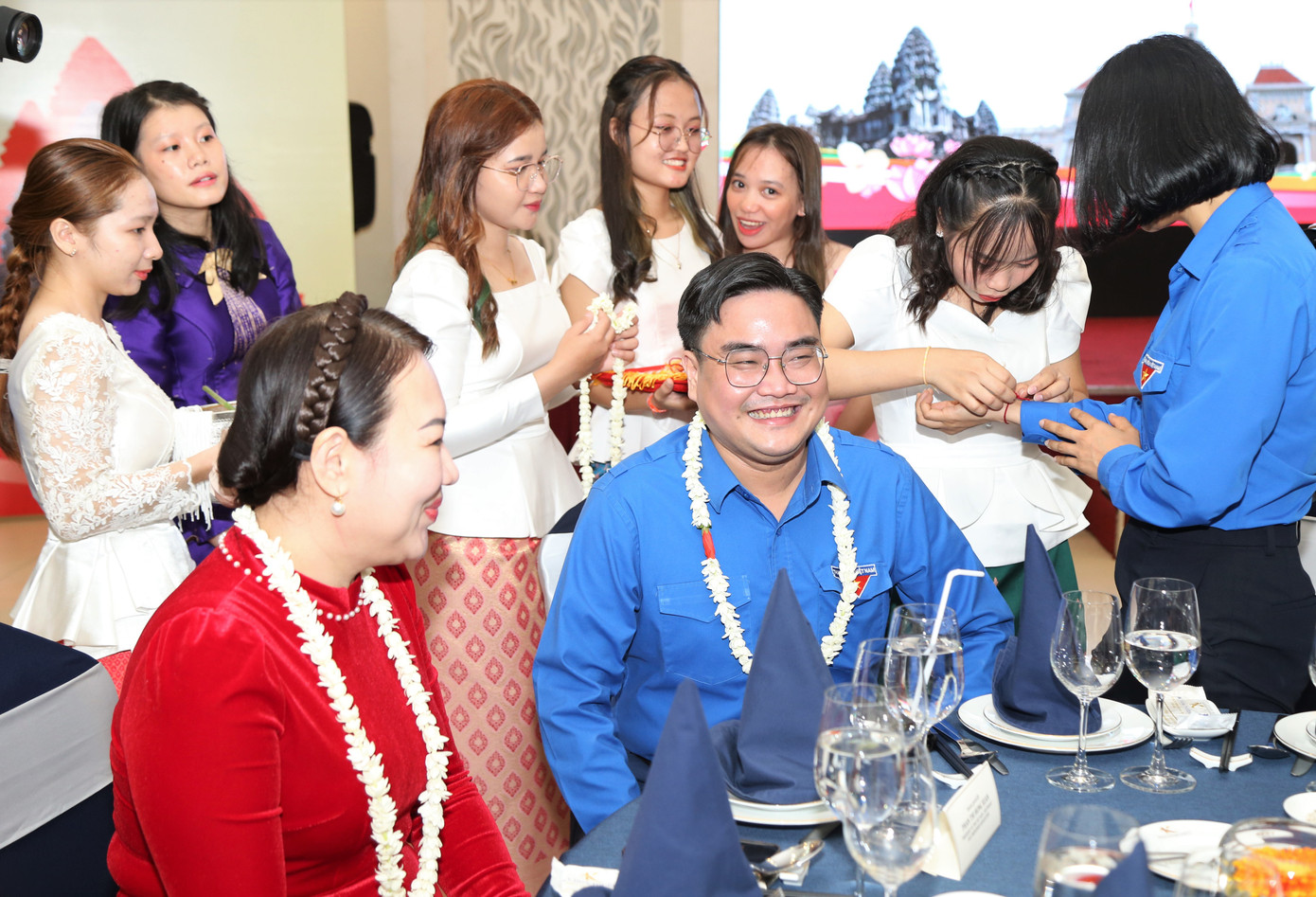 Các bạn sinh viên Lào, Campuchia thực hiện buộc chỉ cổ tay và té nước chúc may mắn đến các đại biểu dự chương trình.
