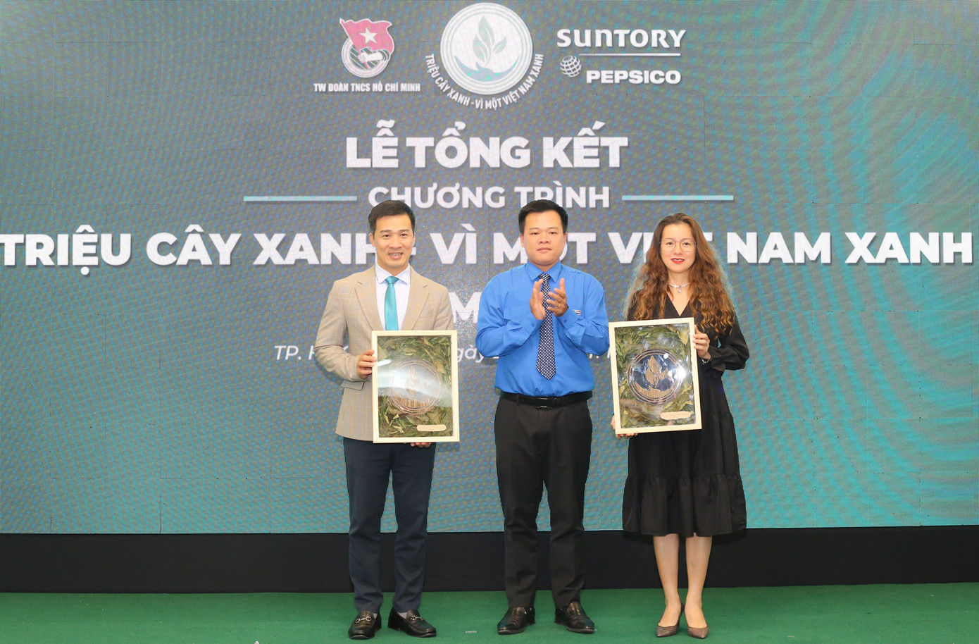 Phó Chánh Văn phòng Trung ương Đoàn Nguyễn Hải Nam (giữa) trao bức tranh “Kết nối màu xanh” đến các đơn vị đồng hành chương trình “Triệu cây xanh – Vì một Việt Nam xanh”. Tác phẩm được thực hiện bằng cách thu thập và lưu giữ những cành cây sau mỗi lần cắt tỉa định kỳ tại các điểm trồng cây trong hành trình vừa qua. Phó Chánh Văn phòng Trung ương Đoàn Nguyễn Hải Nam (giữa) trao bức tranh “Kết nối màu xanh” đến các đơn vị đồng hành chương trình “Triệu cây xanh – Vì một Việt Nam xanh”. Tác phẩm được thực hiện bằng cách thu thập và lưu giữ những cành cây sau mỗi lần cắt tỉa định kỳ tại các điểm trồng cây trong hành trình vừa qua.