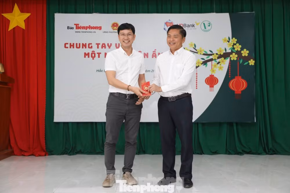 Nhà báo Trần Ngọc Lâm - Phó Trưởng Cơ quan đại diện báo Tiền Phong tại TP. HCM (bên trái) tặng quà Tết cho đại diện chính quyền địa phương.