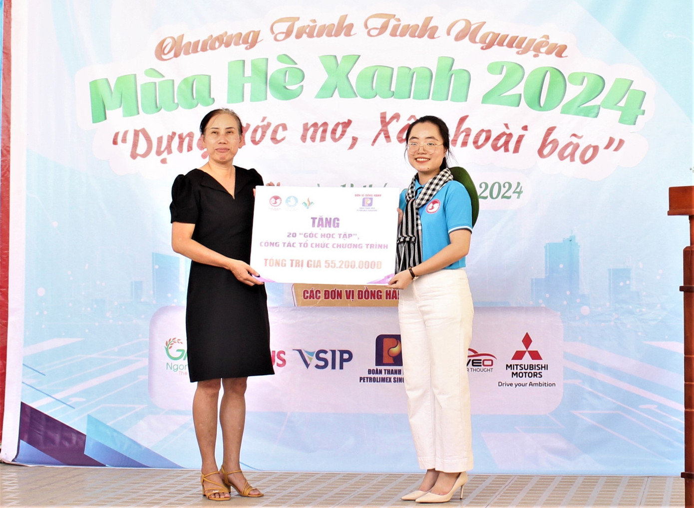 Chị Nguyễn Thúy Quỳnh - Chủ tịch Hội Sinh viên Việt Nam tại Singapore (phải) trao bảng tượng trưng công trình 20 góc học tập cho Hiệu trưởng trường Tiểu học Hòa Lộc.