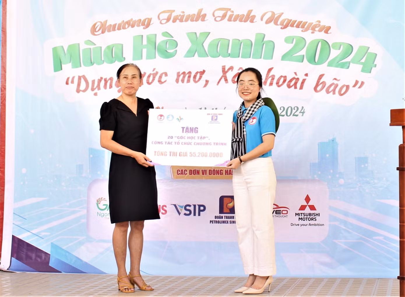 Chị Nguyễn Thúy Quỳnh - Chủ tịch Hội Sinh viên Việt Nam tại Singapore (phải) trao bảng tượng trưng công trình 20 góc học tập cho Hiệu trưởng trường Tiểu học Hòa Lộc.