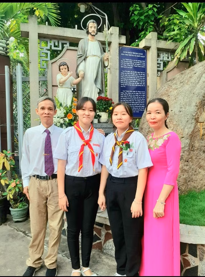 Vũ Nguyễn Ngân Khánh cùng ba mẹ trong lễ vào đời của cô, theo Đạo Công Giáo. (Ảnh: NVCC)