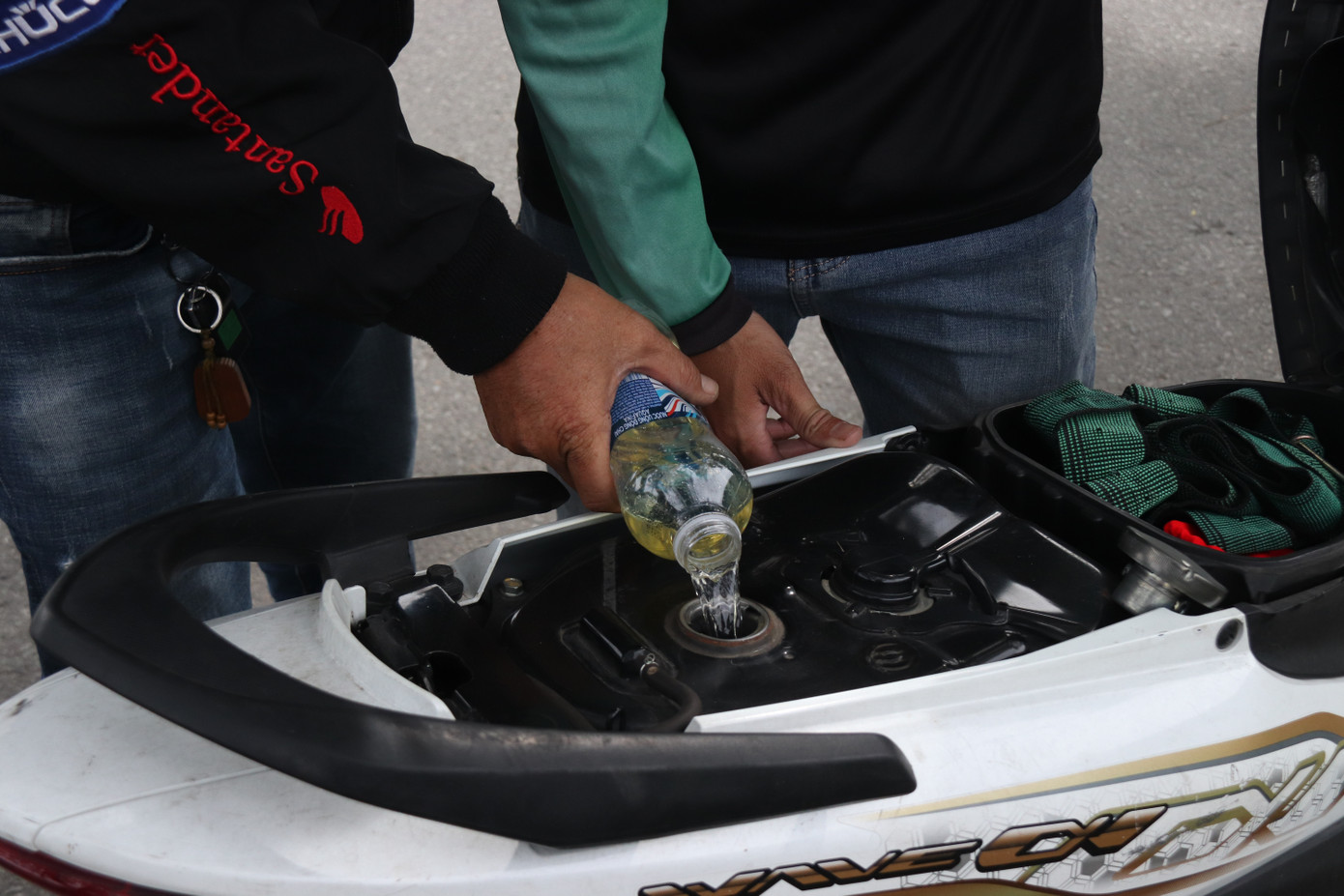 Gặp người hết xăng giữa đường, ông Long không ngần ngại bơm xăng từ xe mình qua cho họ.