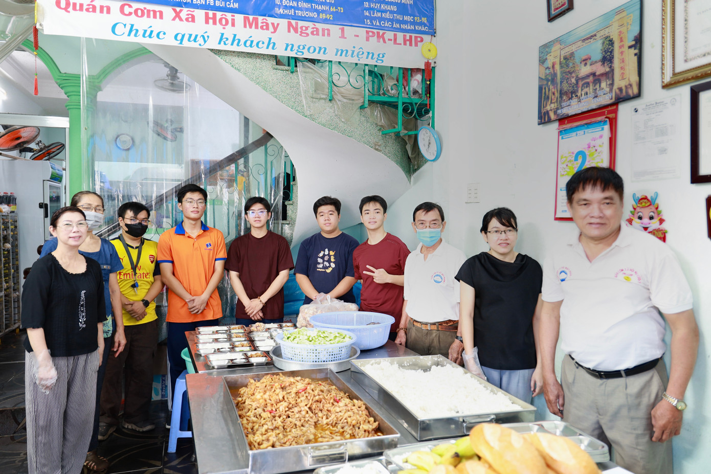 Sinh viên Trường Đai học Bách khoa chụp hình tại quán cùng với ông Nghĩa (ngoài cùng, bên phải) và các tình nguyện viên cố định. (Ảnh: Thùy Trân)