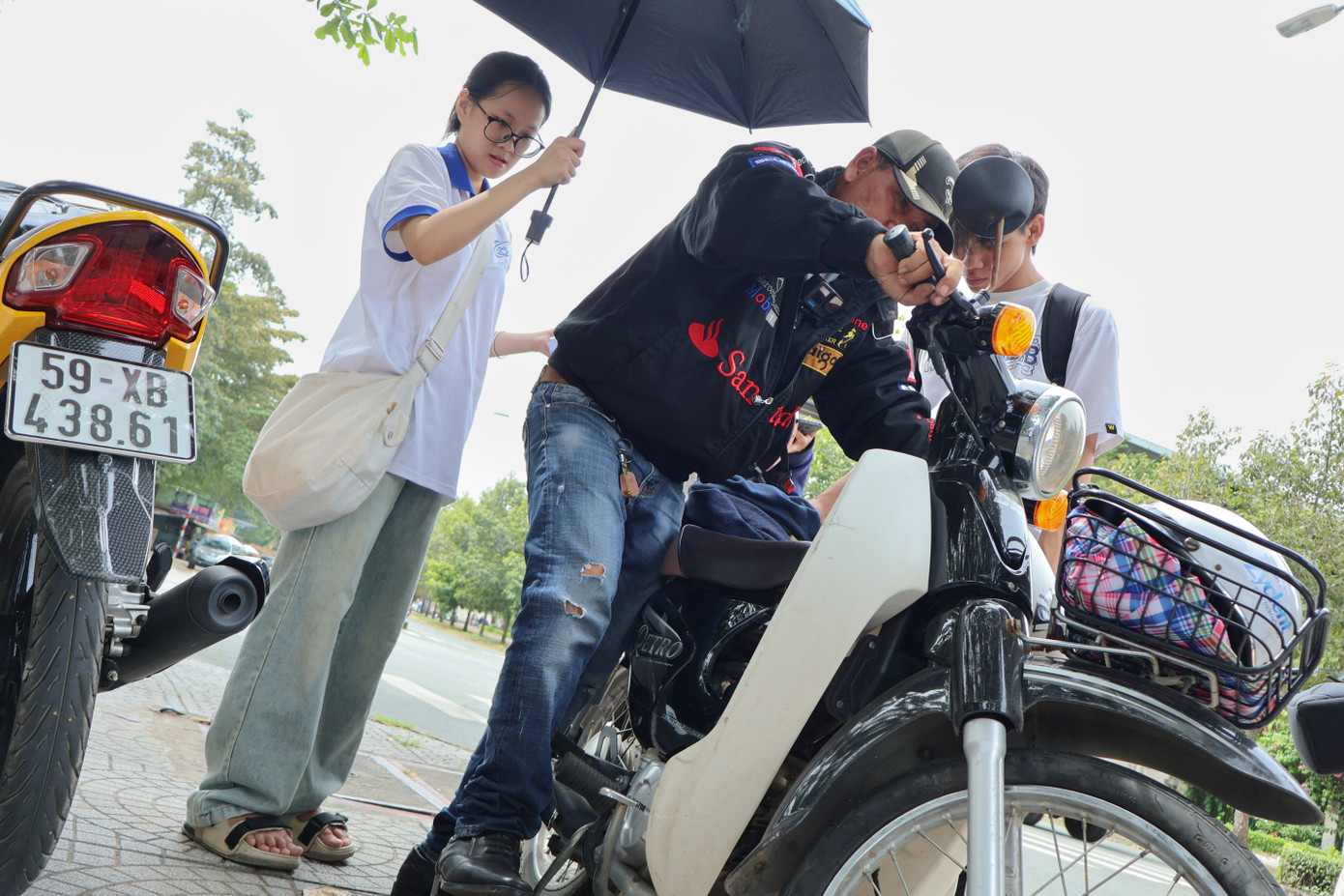 Các bạn sinh viên trường ĐH Công nghệ thông tin hỗ trợ ông che nắng, quạt… khi ông giúp các bạn sửa xe.