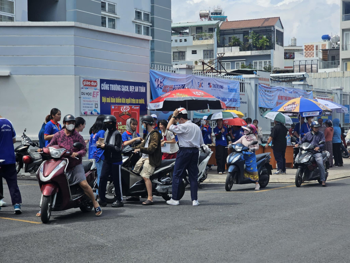 Dưới cái nắng ban chiều, những bạn sinh viên tình nguyện túc trực trước điểm thi, đồng hành cùng các bạn thí sinh vào làm thủ tục.