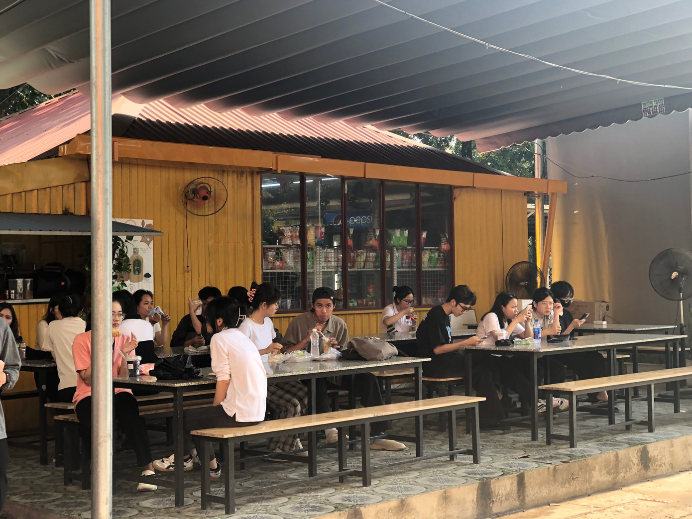 Ngồi dưới quạt và vòi nước phun sương là một cách để giải nhiệt của sinh viên vào mùa này.