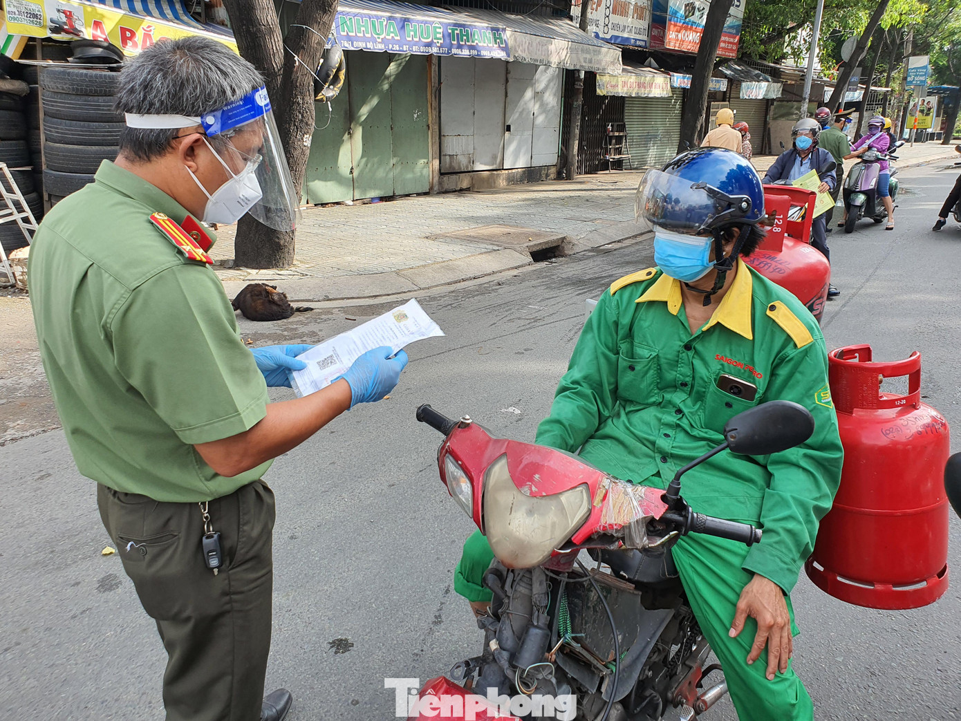 Cán bộ công an kiểm tra giấy đi đường của nhân viên chở ga