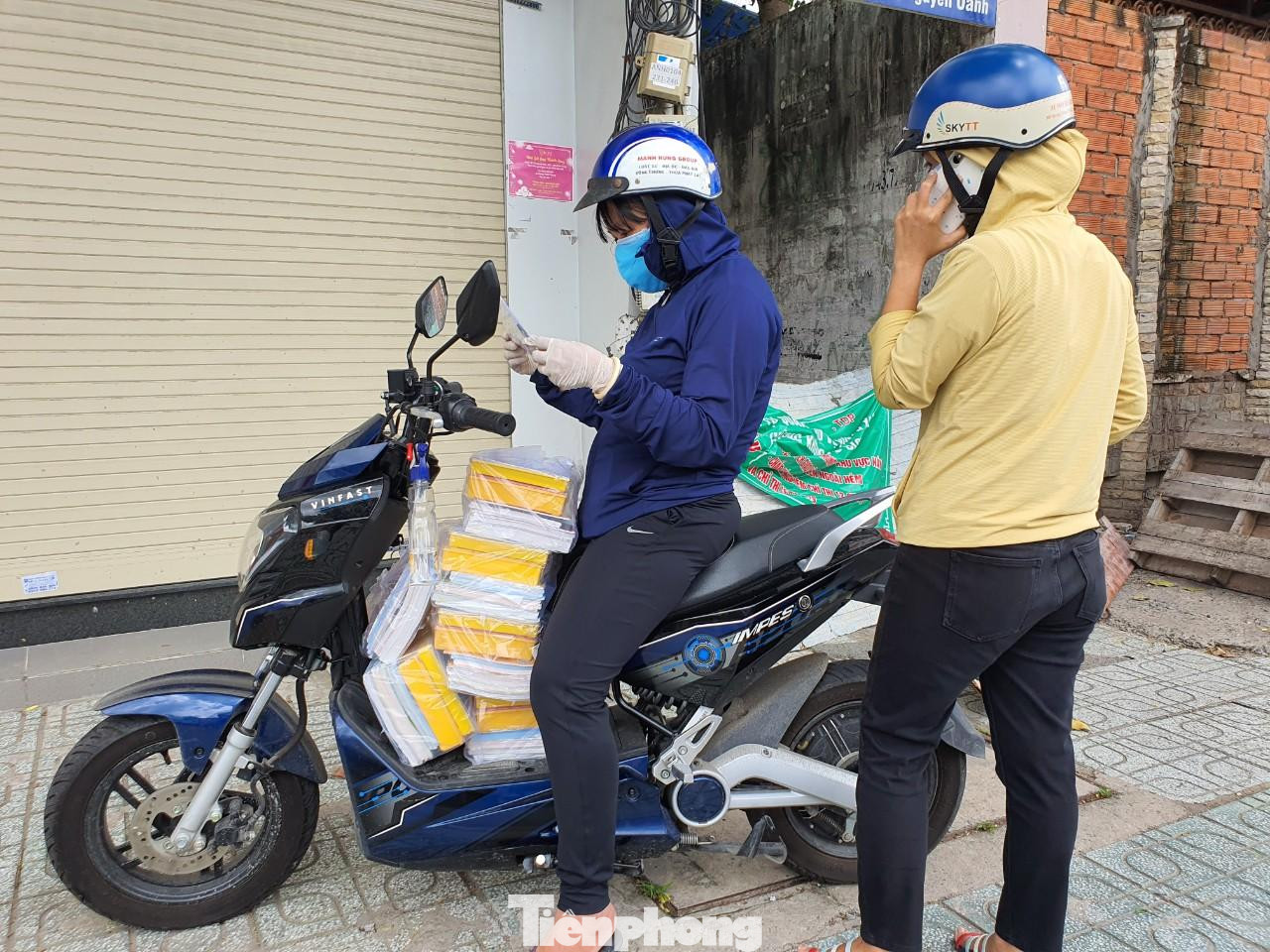 Hai giáo viên, nhân viên của Trường Tiểu học Võ Thị Sáu nhận nhiệm vụ giao SGK đến học sinh ngày 9/9