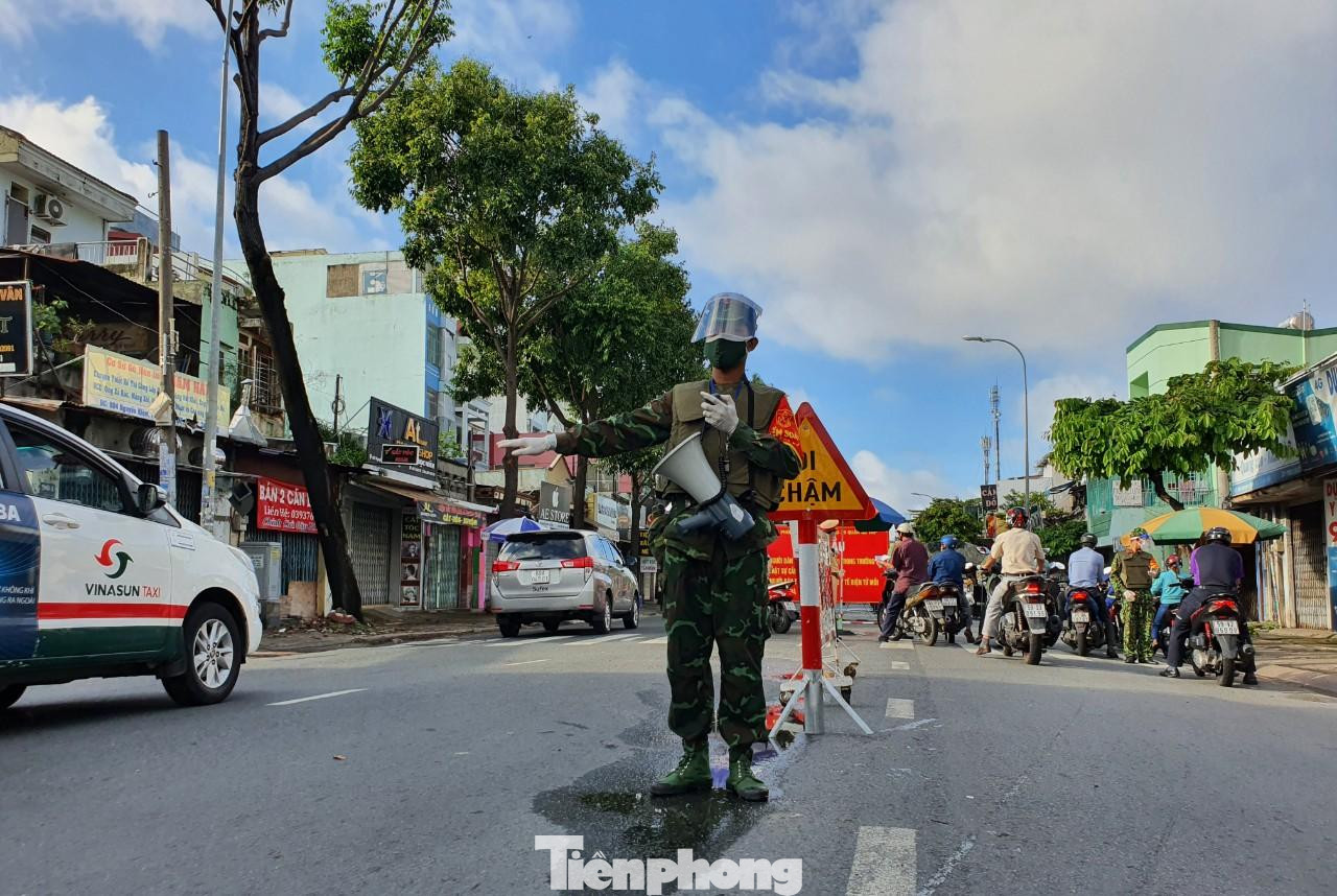 Tương tự, ghi nhận ở nhiều chốt kiểm soát dịch khác trên các tuyến đường như Nguyễn Oanh (quận Gò Vấp); đường Hoàng Minh Giám, đường Nguyễn Văn Trỗi (quận Phú Nhuận)… lượng người đi đường cũng giảm rất nhiề.u Tuy nhiên, vẫn có một số trường hợp ra không có giấy đi đường vẫn ra đường không có lý do chính đáng và bị lập biên bản xử phạt. Trong ảnh: Một chiến sĩ quân đội phân luồng giao thông