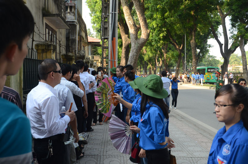 Những sinh viên tình nguyện quạt cho người dân đang xếp hàng
