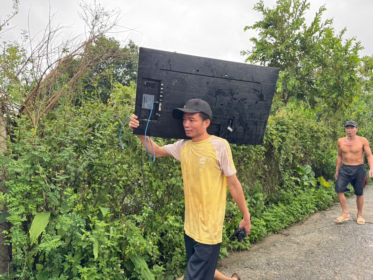 Một người dân vác ti vi lên bờ chạy lũ