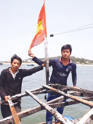 Anh Thạnh và anh Phải bên lá cờ Tổ quốc. Ảnh: Nguyễn Thành