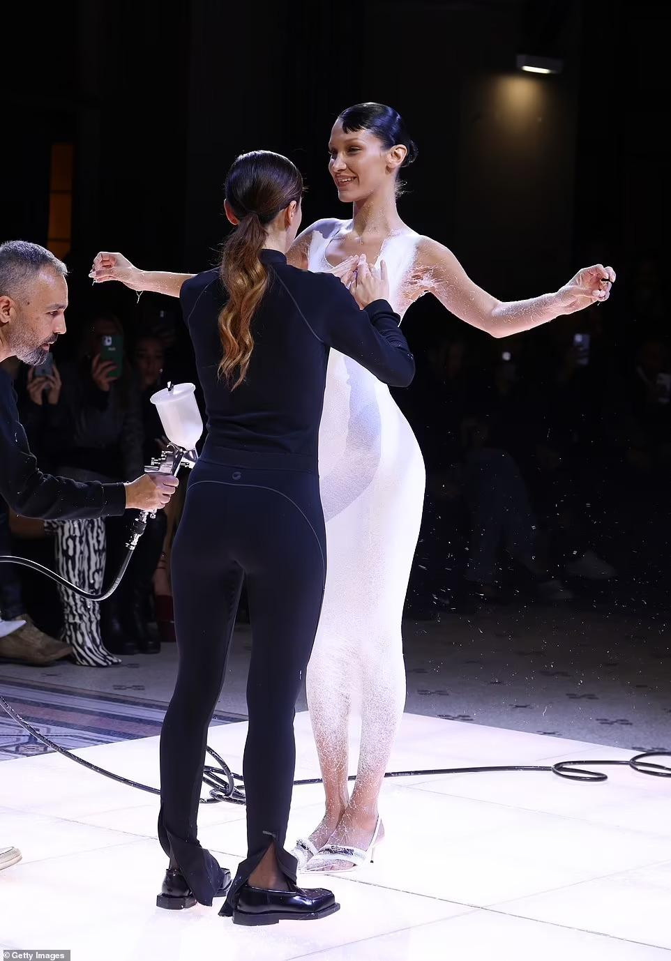 Sau đó, một nữ nhân viên xuất hiện để hoàn thiện chiếc váy phun sơn, bao gồm tạo hình cổ váy và làm sạch những lớp mủ dư thừa. Ảnh: Getty Images.