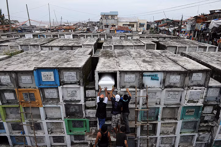 Công nhân đặt một chiếc quan tài vào ngôi mộ trên cao trong nghĩa trang ở Navotas, Manila, Philippines