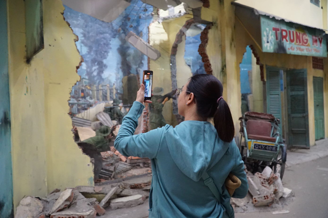 Một bạn trẻ đang chụp hình cảnh đổ nát của hộp minh hoạ cuộc chiến Mậu Thân