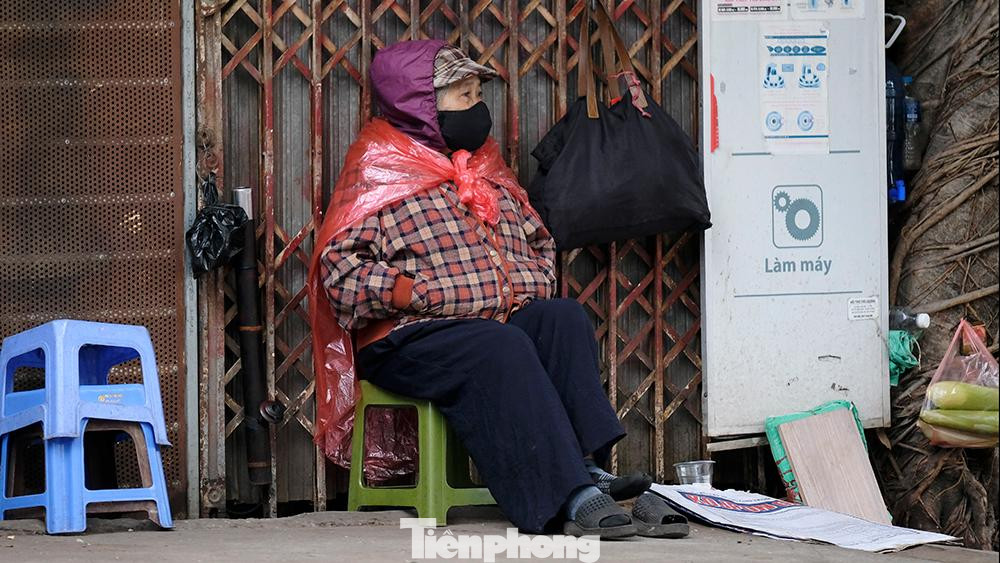 Một cụ bà phải khoác thêm cả áo mưa để tránh gió trong buổi sáng mùa đông giá lạnh. Một cụ bà phải khoác thêm cả áo mưa để tránh gió trong buổi sáng mùa đông giá lạnh.