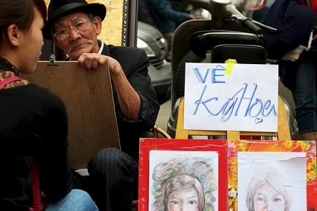 Họa sĩ vẽ chân dung – Tác giả người Canada Jennifer Holmes Beamer chụp tại Hà Nội. “Băng qua những con phố đông đúc ở Hà Nội, tôi nhìn thấy người họa sĩ già này. Vẻ tập trung cao độ trên khuôn mặt ông và sự hứng thú khi tay đưa bút vẽ khiến tôi tưởng như ông đang sống trong một thế giới riêng tịch mịch không liên quan gì tới phố phường huyên náo.” 