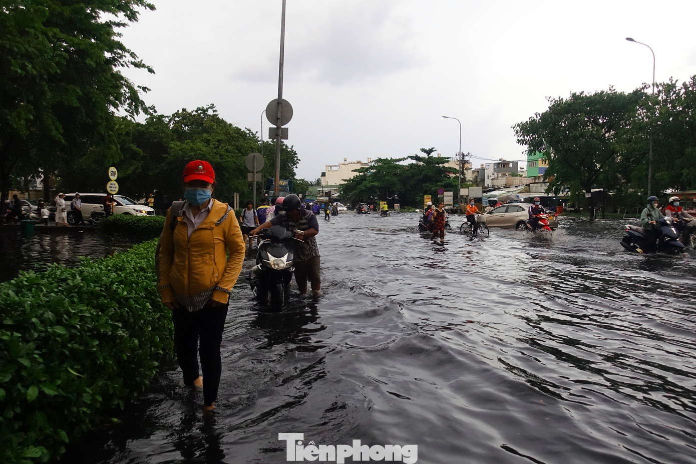 Người và phương tiện di chuyển lên vỉa hè và các vị trí cao ráo để vượt qua khu vực bị ngập trên đường.