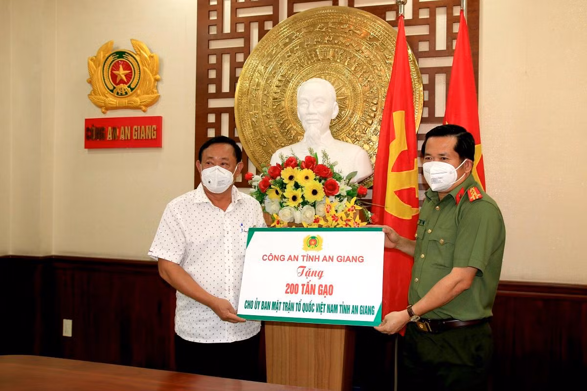 Đại tá Đinh Văn Nơi - Giám đốc Công an tỉnh An Giang trao bảng tượng trưng 200 tấn gạo cho ông Nguyễn Tiếc Hùng - Chủ tịch UBMTTQVN tỉnh An Giang.