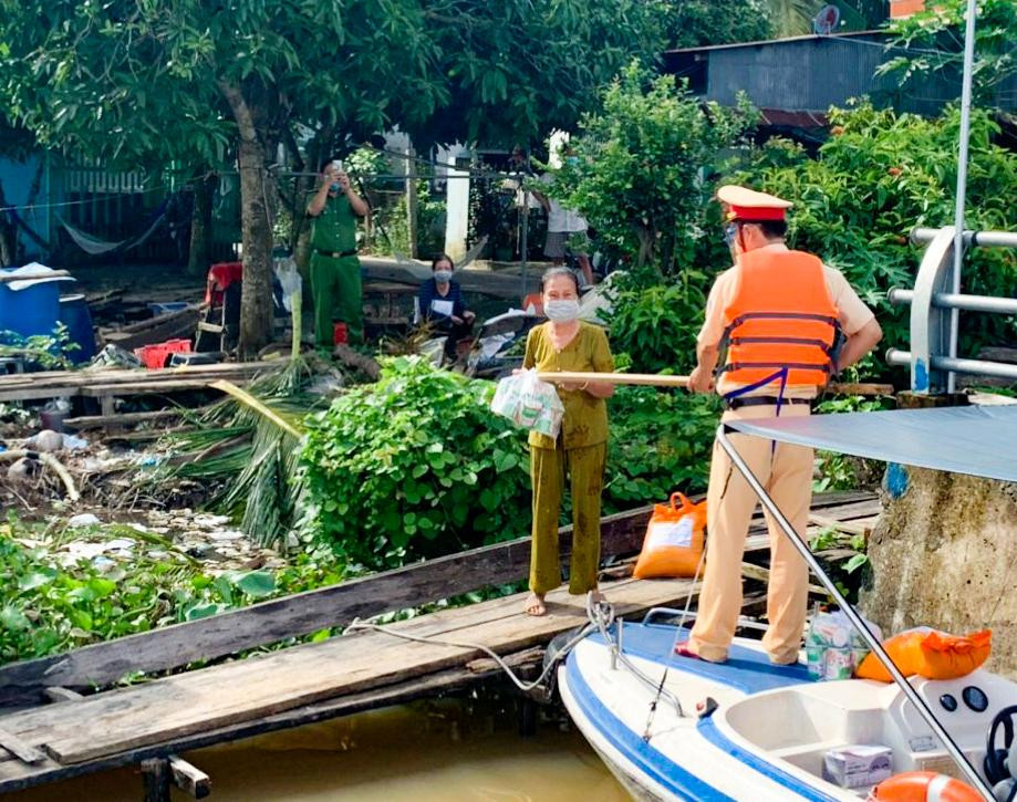 Một cán bộ đi ca nô đến trao quà cho người dân.