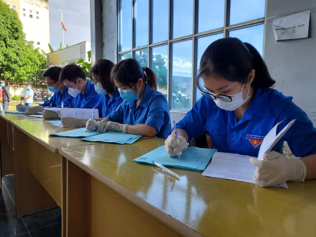 Lực lượng Đoàn viên thanh niên hỗ trợ ghi thông tin vào phiếu tiêm chủng cho người dân - Ảnh: Kim Hà.