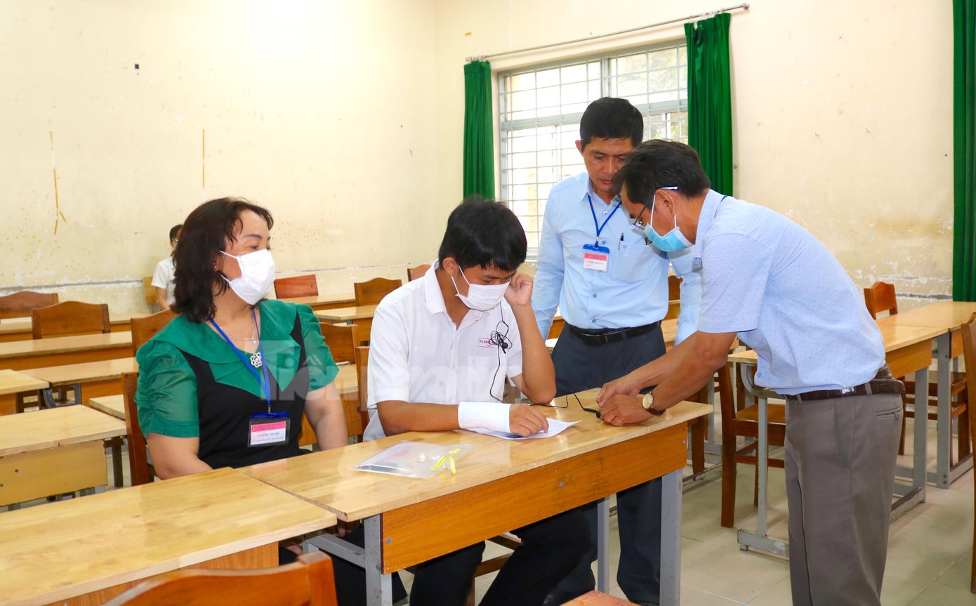 Cán bộ coi thi gắn máy thu tiếng cho em Tạ Quốc Hùng - Ảnh: Kim Hà.