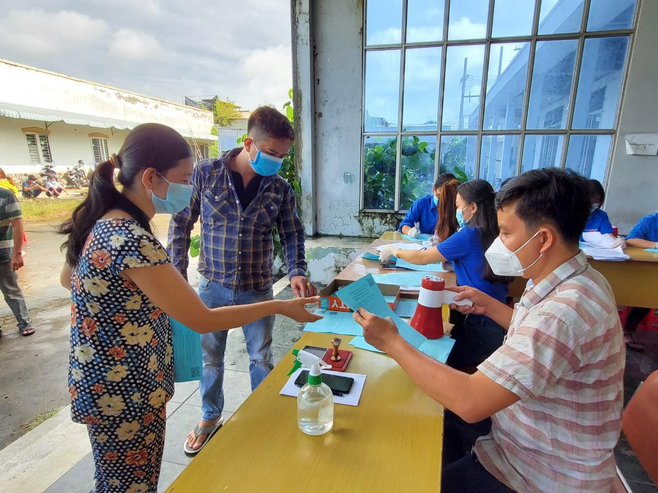 Trả phiếu tiêm chủng cho người dân. Ảnh: Kim Hà.