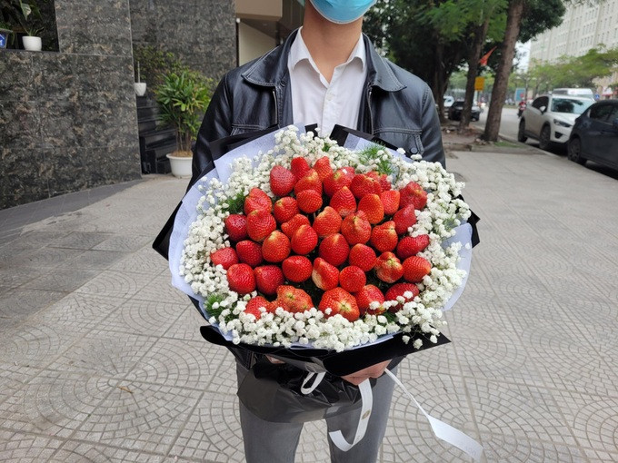 Một khách hàng nam mua bó "hoa dâu tây" chiều 7/3. (Ảnh: H. T).