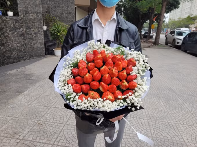 Một khách hàng nam mua bó "hoa dâu tây" chiều 7/3. (Ảnh: H. T). Một khách hàng nam mua bó "hoa dâu tây" chiều 7/3. (Ảnh: H. T).