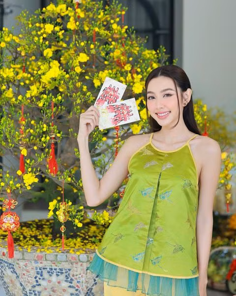 Khoảnh khắc dễ thương của Hoa hậu Nguyễn Thúc Thùy Tiên trong sáng mùng 1 Tết. Cô diện thiết kế cổ yếm khoe vai trần gợi cảm.