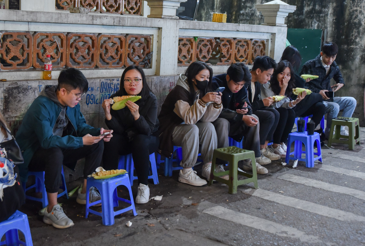 Hàng dài bạn trẻ ngồi thưởng thức ngô nướng.