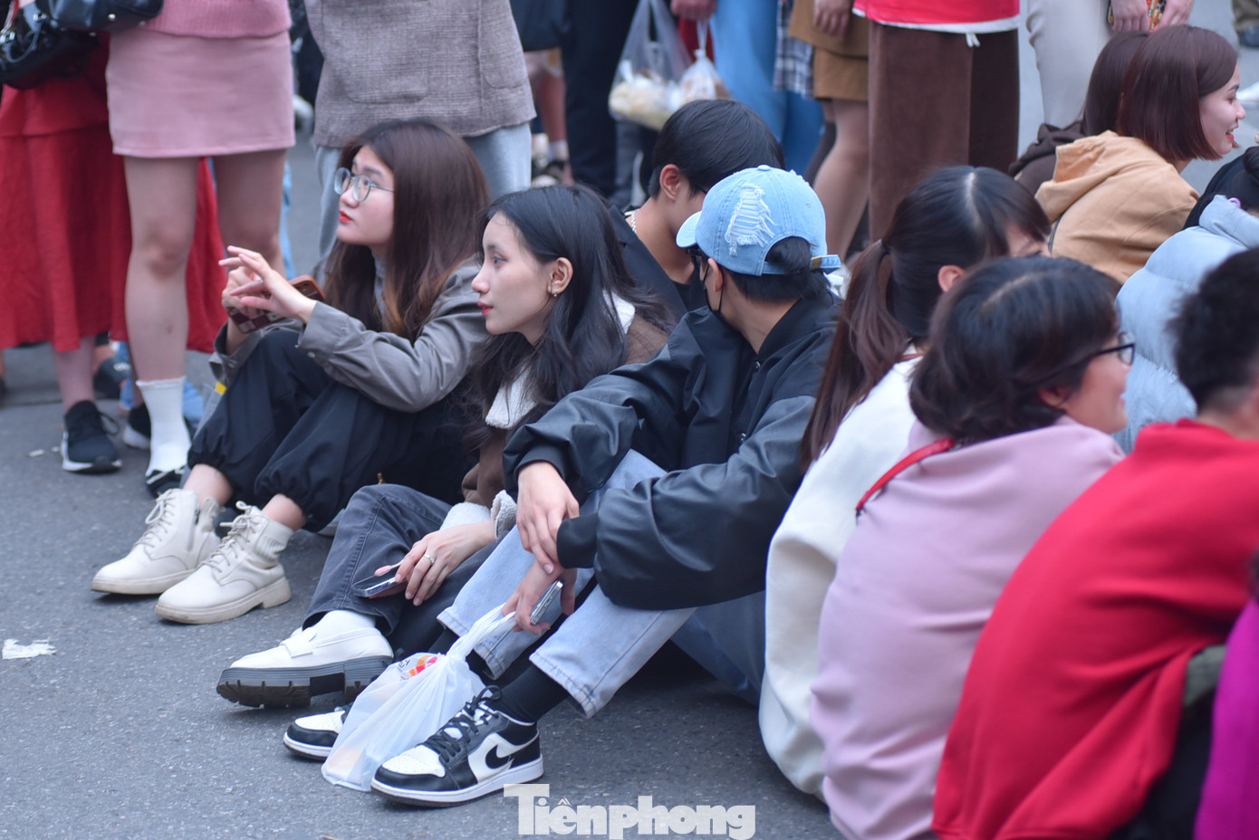 Một số bạn trẻ ngồi bệt trên phố đi bộ.