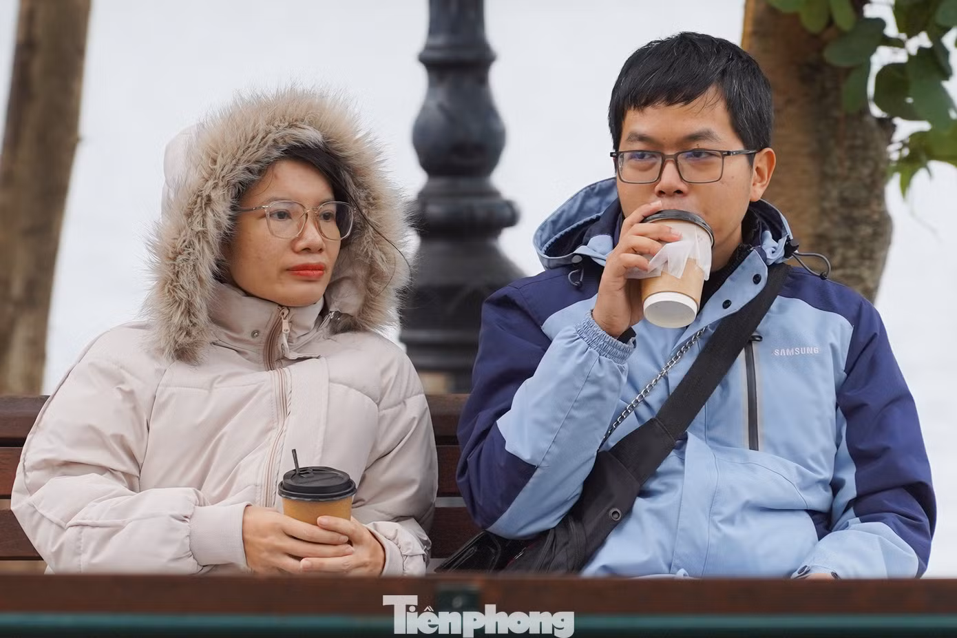 Người dân thư giãn ngồi bên hồ Gươm trong không khí lạnh.