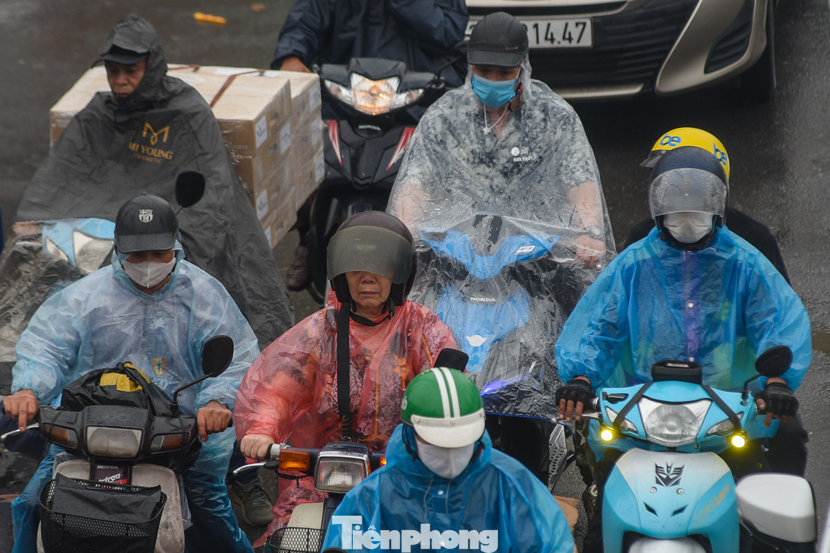 Người điều khiển xe máy trùm kín áo mưa, chen chúc, chờ đợi để được di chuyển và thoát khỏi cảnh trời mưa tắc đường.