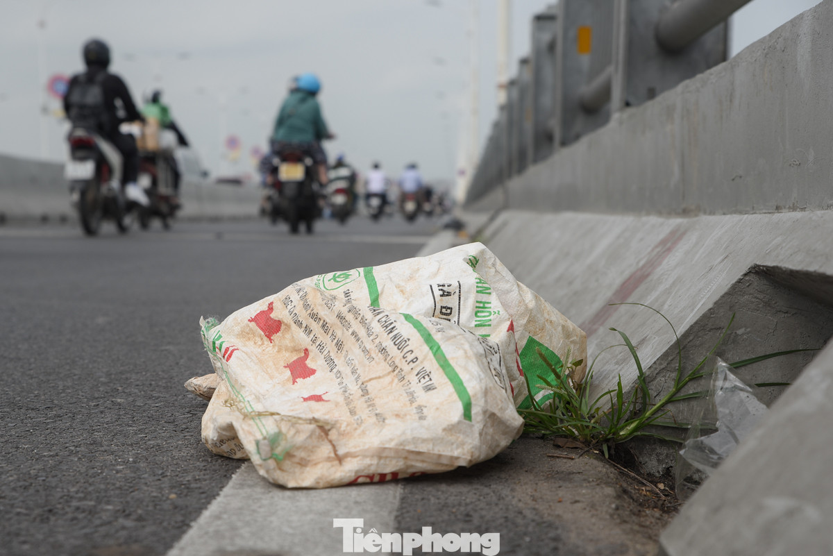 Rác thải sinh hoạt vứt bừa bãi dưới mặt đường, trên lan can cầu Vĩnh Tuy.