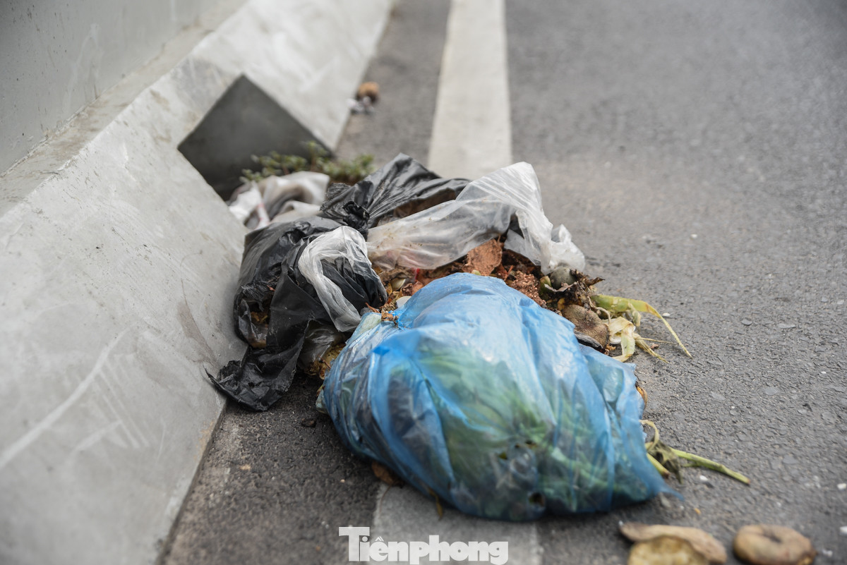 Rác thải sinh hoạt vứt bừa bãi dưới mặt đường, trên lan can cầu Vĩnh Tuy.