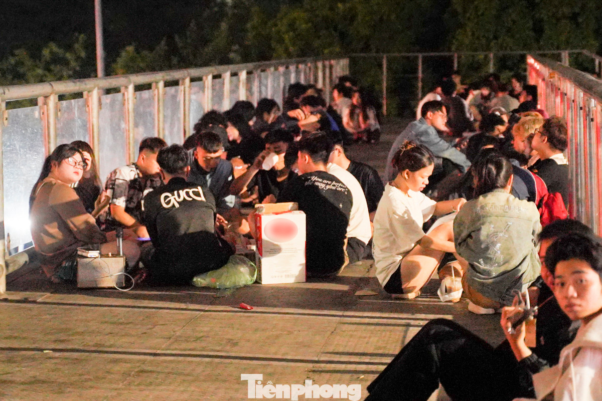 Hơn 1 giờ sáng, trên cầu vượt dành cho người đi bộ ở nút giao Mai Dịch trên đường Hồ Tùng Mậu (quận Cầu Giấy, Hà Nội) rất đông người tụ tập, trải chiếu ngồi kín cả mặt cầu để ăn uống, đánh bài.