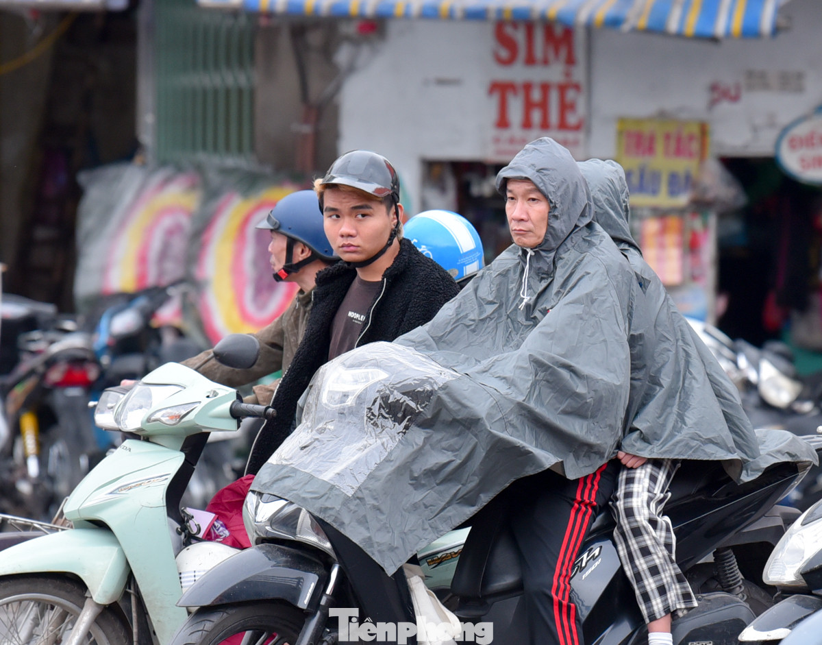 Một số người phải mặc áo mưa khi ra đường để tránh rét.