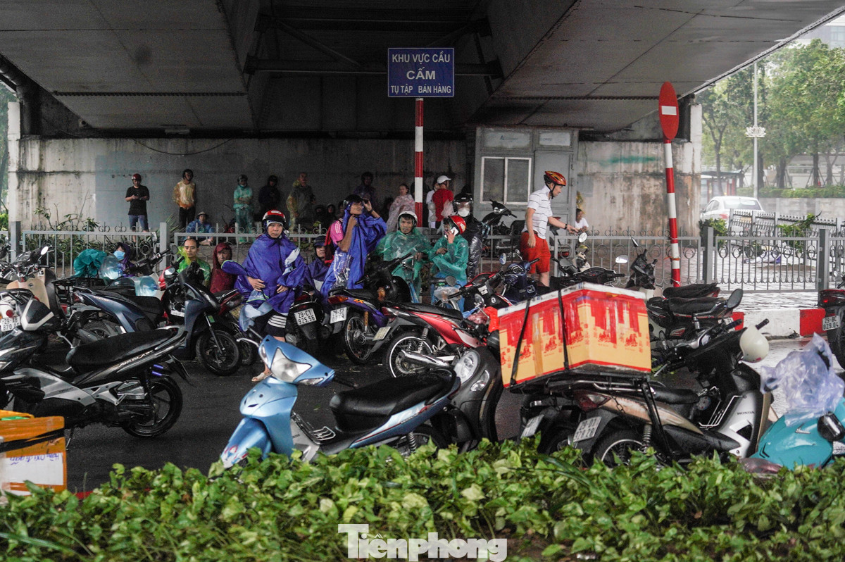 Rất đông người dân đứng tránh mưa dưới gầm cầu.