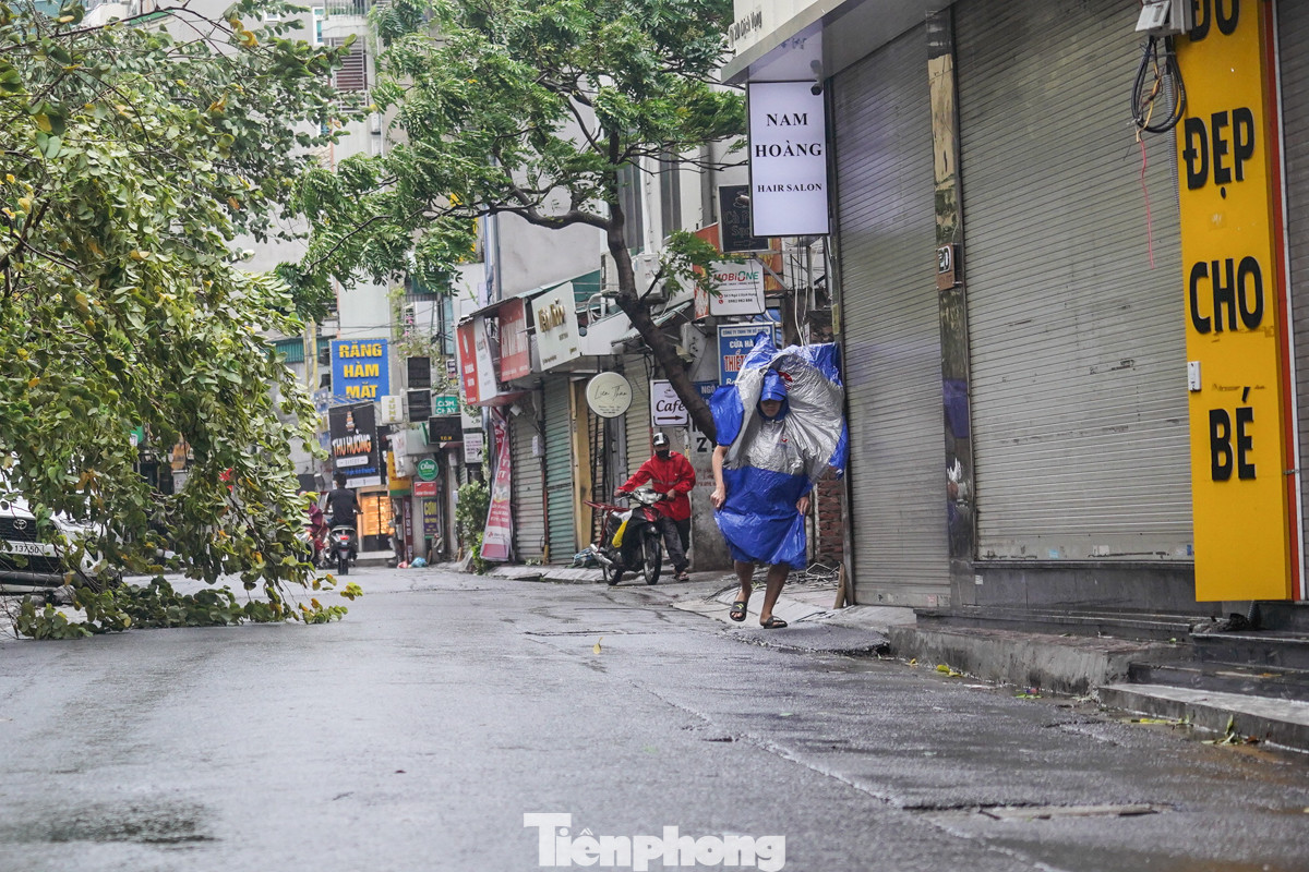 Gió quật mạnh giật tung áo mưa của người đi đường, một số người phải dắt bộ xe máy qua những đoạn đường gió to.