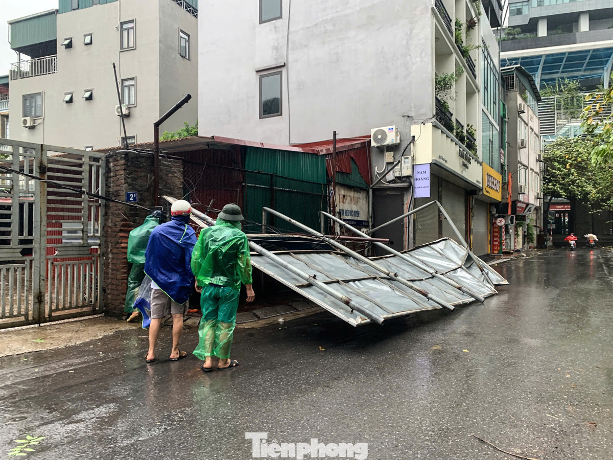 Một biển hiệu lớn bằng tôn trên đường Dịch Vọng đã bị gió giật mạnh quật đổ.