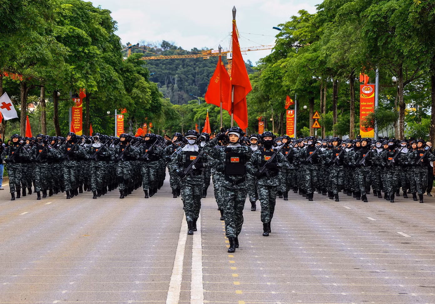 Khối nữ chiến sĩ cảnh sát đặc nhiệm mặc quân phục ngụy trang kỹ thuật số màu xanh rêu, đội mũ bảo hiểm đen gắn bộ đàm, đeo áo giáp mềm và trang bị súng tiểu liên MP5.