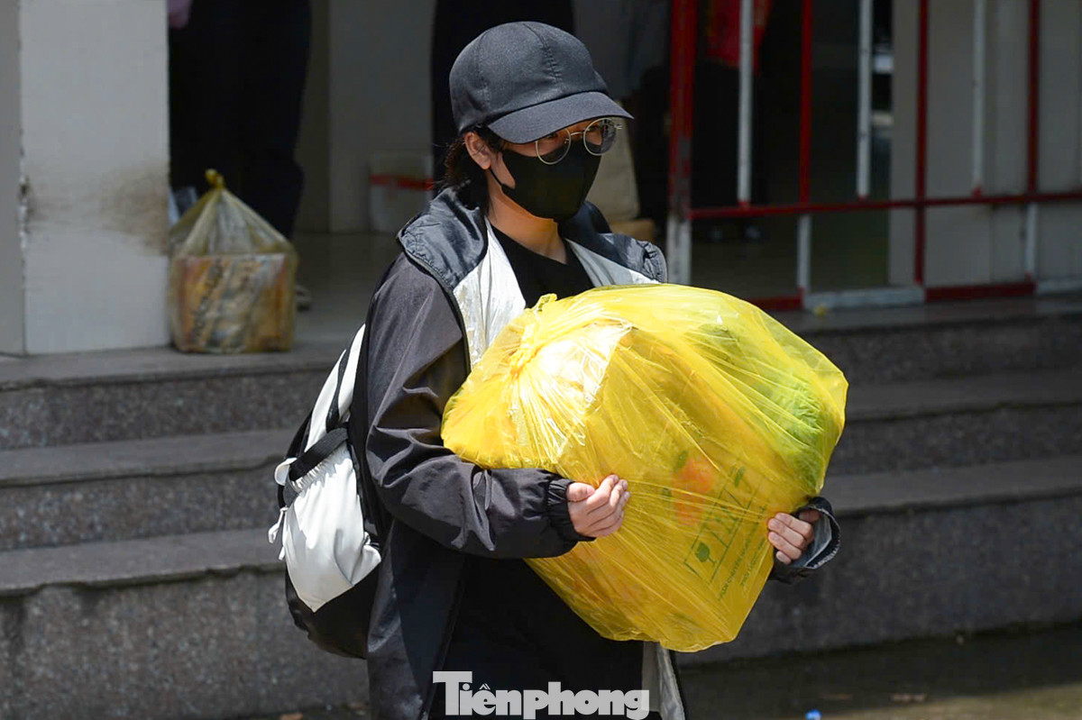 Mọi người khệ nệ vác theo hành lý và quà quê rời bến xe trong thời tiết nắng nóng.