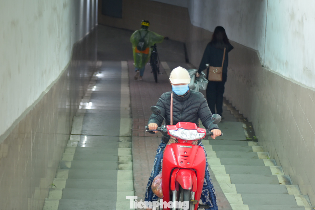 Một chiếc xe máy đi hẳn xuống hầm chui để tránh kẹt xe, mưa lạnh.