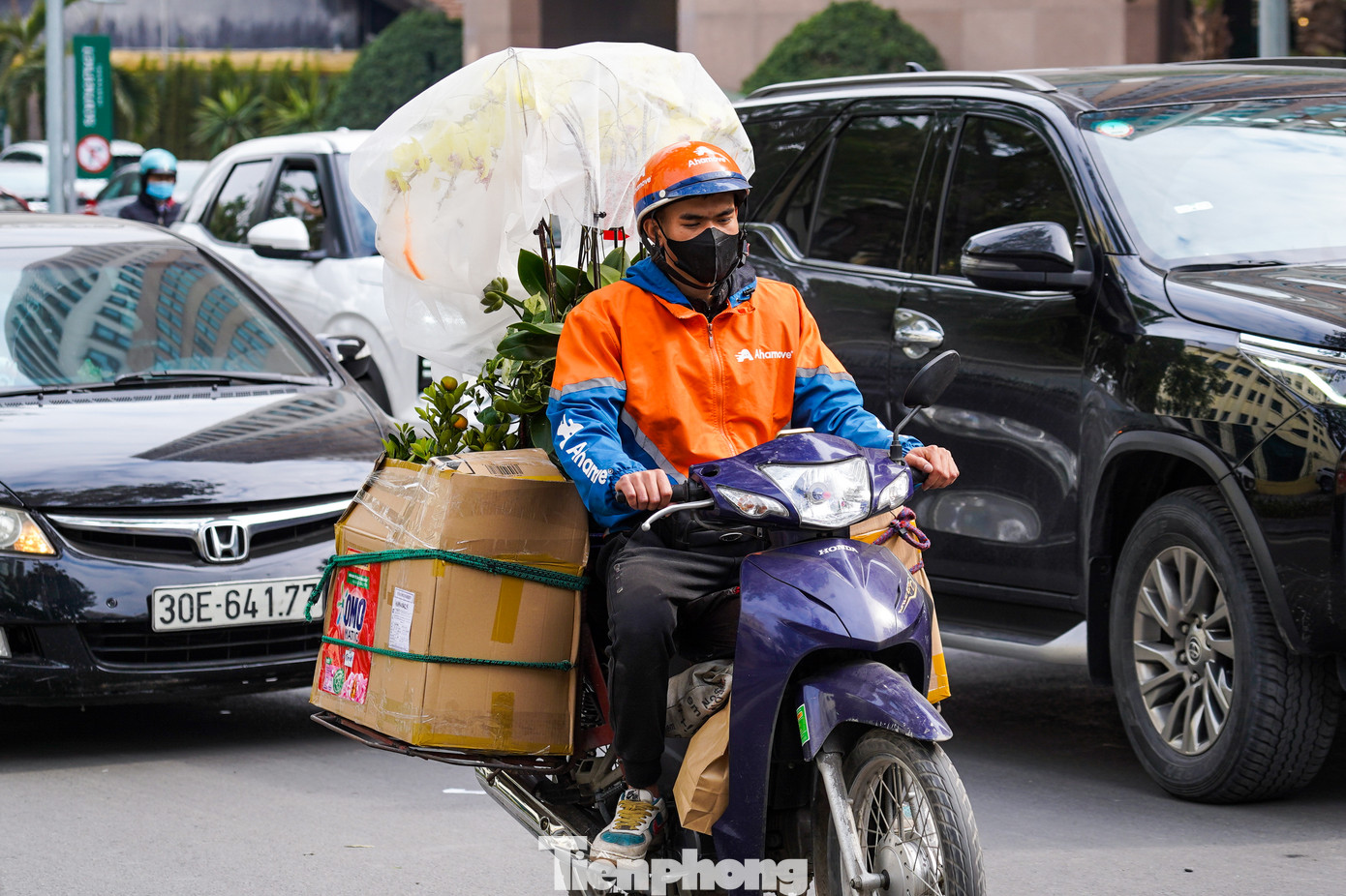 Nhiều lái xe với hàng Tết cồng kềnh, len lỏi giữa đám đông phương tiện di chuyển trên đường.