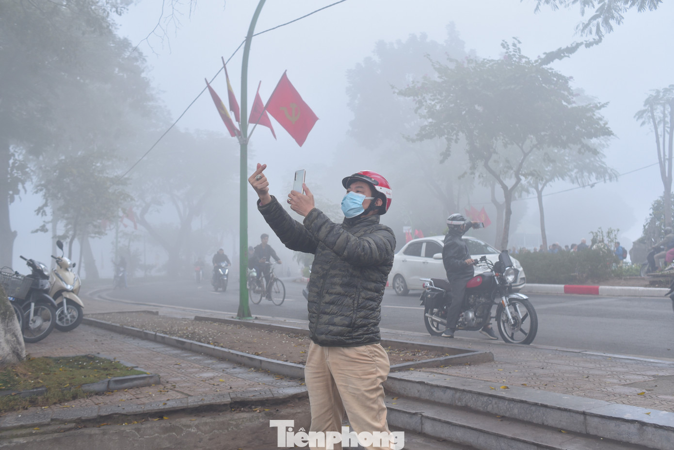 Một người đàn ông vừa thả tim, vừa chụp ảnh với bầu trời Hà Nội sương mù.